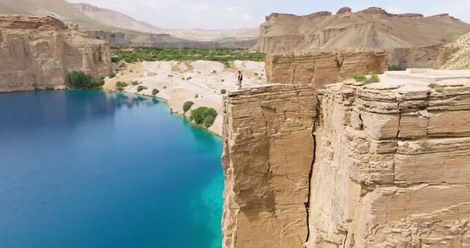 Person On Cliff Edge Over Blue Lakes Of Band-e-Amir National Park In Bamyan, Afghanistan. Aerial Drone Shot