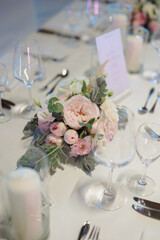 A beautifully arranged wedding table centerpiece with pink and white flowers on a pristine white tablecloth.