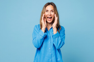 Young woman 50s years old wear shirt casual clothes scream sharing hot news about sales discount with hands near mouth isolated on plain pastel light blue cyan background studio. Lifestyle concept.