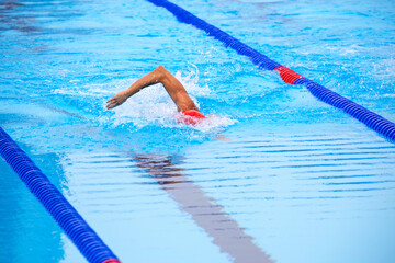 Unrecognizable young male athlete swimming using front crawl in an Olympic-size swimming pool