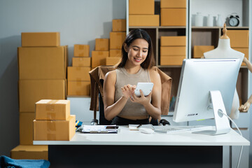 Entrepreneur using calculator in her hand, calculating financial expense at home office, online market packing box delivery,Startup successful small business owner, SME, concept.