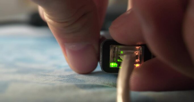 Man disconnects an Internet cable to a laptop using an adapter. Ethernet cable adapter with green and yellow LED. Internet cable connection. Internet cable through an adapter connected to laptop