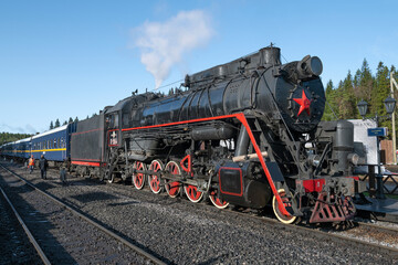 The old steam locomotive L-5164 with the retro train on the Ruskeala Mountain Park station on a sunny October day. Karelia