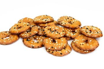 Salted round pretzels with black and white sesame isolated on white. Cracker chips with sea salt isolated on white background. Round shape appetizers. Salty crackers with sesame isolated.