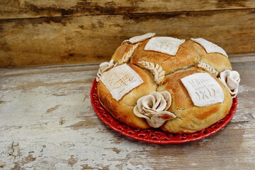 Homemade decorated Serbian slava bread on rustic wooden board.