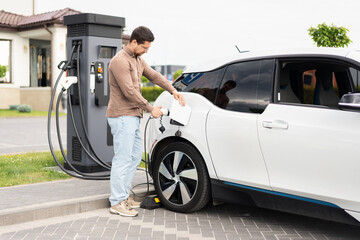 Man Charging Electric Car At Station, Sustainable Energy
