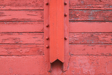 Old cracked wall made of wooden panels fastened with metal shape painted in red as a background