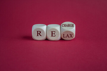 Relax and recharge symbol. Turned a cube and changes the word 'relax' to 'recharge'. Beautiful pink background. Business, relax and recharge concept.