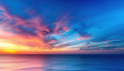 Obraz premium A beautiful sunset over the ocean with a few clouds in the sky