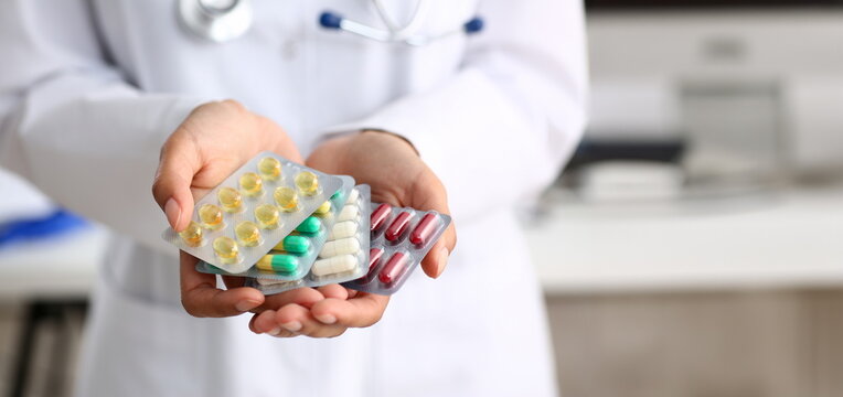 Female doctor hand holding pack of different tablet blisters at workplace closeup. Panacea life save service prescribe medicament legal drug store disease healing blood pressure concept
