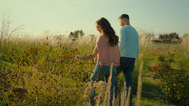 Romantic honeymoon. Happy family loving married Caucasian couple male husband man female wife woman holding hands stroll walking talk planning future together enjoying nature farmland field vacation