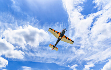 View of an aerobatic plane (aerodyne), in flight under a blue sky with white clouds. flight...