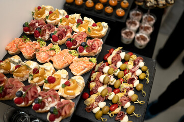 Buffet snacks. Bruschettas, canapes and sandwiches on table. Appetizers with jamon, prosciutto,...