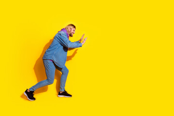 Full length profile portrait of nice young man push empty space wear denim jacket isolated on yellow color background