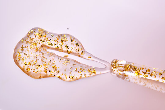Pipette with 24k gold serum on a pink background.