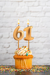 Cupcake with number 61 birthday candle - White block wall background