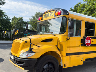 Shot of retro-styled yellow school bus with extended red stop sign standing still on serene road, empty vehicle with no driver awaiting children to boarding, transportation concept, copy space