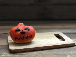 Delicious chocolate glazed donuts,decorated like a Pumpkin on wood,for funny Halloween...