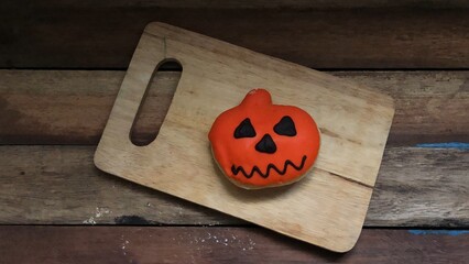 Delicious chocolate glazed donuts,decorated like a Pumpkin on wood,for funny Halloween...