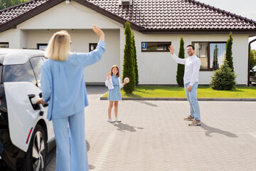 Fototapeta premium Family Saying Goodbye Outside Modern House, Waving Hands And Smiling