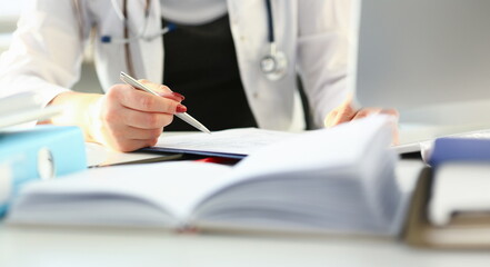 Female doctor hand hold silver pen filling patient history list at clipboard pad. Physical exam er disease prevention ward round visit check 911 prescribe remedy healthy lifestyle concept