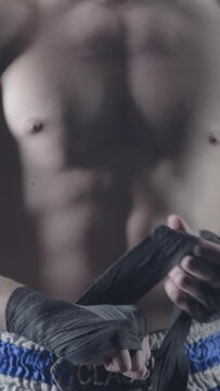 Closeup of a mixed martial arts fighter wrapping his hands before a fight. Boxer wraps his hand a red bandage before the figh