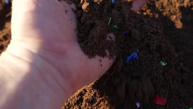 Microplastic pollution. Microplastics in ground. Soil contaminated with microplastics. Plastic waste in soil, earth. Environmental, groundwater disaster. Plastic waste in ground at agricultural field.