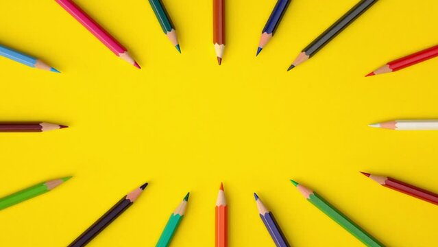 Looping stop motion animation of pencils of different colors moving on yellow paper background with copy space, top view. Back to school concept. Remote education, online study.