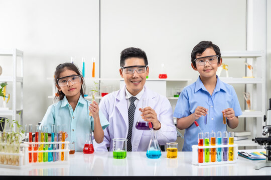 Asian students and teacher conducting science experiments with colorful liquids in the laboratory classroom