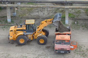 front loader loads gravel mixture into a dump truck