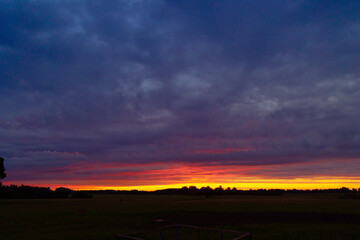 A beautiful minimalist landscape with colorful sunrise skies. Bright summer scenery of rural Latvia, Northern Europe.