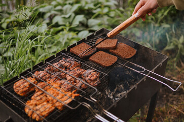 turning grilled pieces of bread and meat using an iron fork on a lake on a summer day