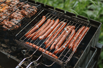 cooking sausages with smoke on a grill in nature on a lake in summer 