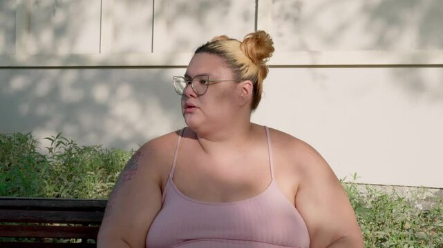 Portrait of a plump woman sitting on the bench relaxing after exercising