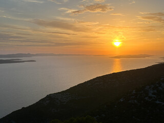Obraz premium Reflection of the setting sun in sea water, view from the mountain. Sunset against the backdrop of the sea and mountains.
