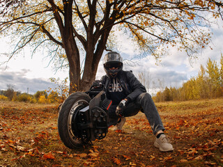 A man in a helmet is holding a monocycle. Electric monowheel is a modern urban transport. Riding in the autumn park © pavelkant