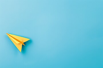 Fototapeta premium The top view photo depicts a yellow paper plane on a turquoise blue background with copy space and center composition.