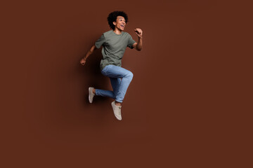 Full body photo of attractive young man running have fun dressed stylish khaki clothes isolated on brown color background