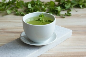 A cup of fresh tea from Chickweed, lat. Stellaria media on white marble. Traditional herb tea rich in minerals is used for detoxificatin, tasty in salads.