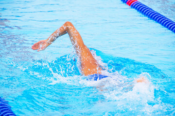 Unrecognizable male swimmer swimming using front crawl in an Olympic-size swimming pool