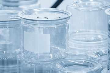 The clear plastic container with aluminum lid in the light blue scene.