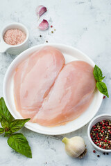 Raw chicken fillet on a plate on a light background with spices and herbs. The concept of proper nutrition, protein, organic meat.