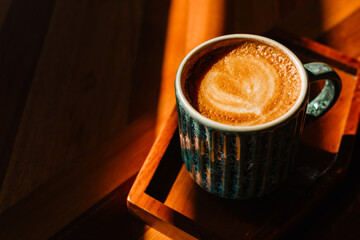 Cappuccino iCappuccino with latte art on a wooden stand with space for textn a mug on a stand