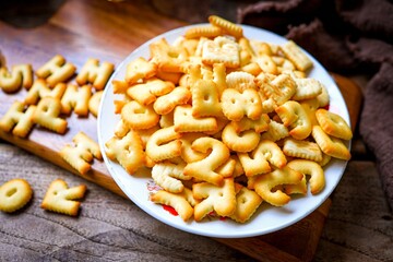  biscuits ABC or abc cracker in a white plate , wooden  background