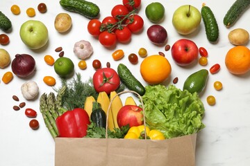 Vegan food delivery. Paper bag with different fresh vegetables and fruits on white marble background, flat lay