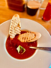 Gazpacho soup with toasted bread on a white plate in a restaurant