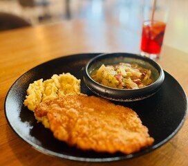 Breaded fish fillet served with mashed potatoes and tomato sauce on wooden table