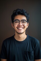 Obraz premium Portrait of an Indonesian young man smiling, wearing glasses and a black t-shirt, with a simple background.