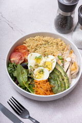 A bowl of couscous, meat, eggs and vegetables angle view