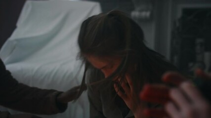 Side handheld shot of boy filming how demon possessing body of his girl friend. Teenager writhing, friends panicking and trying to help her in abandoned house